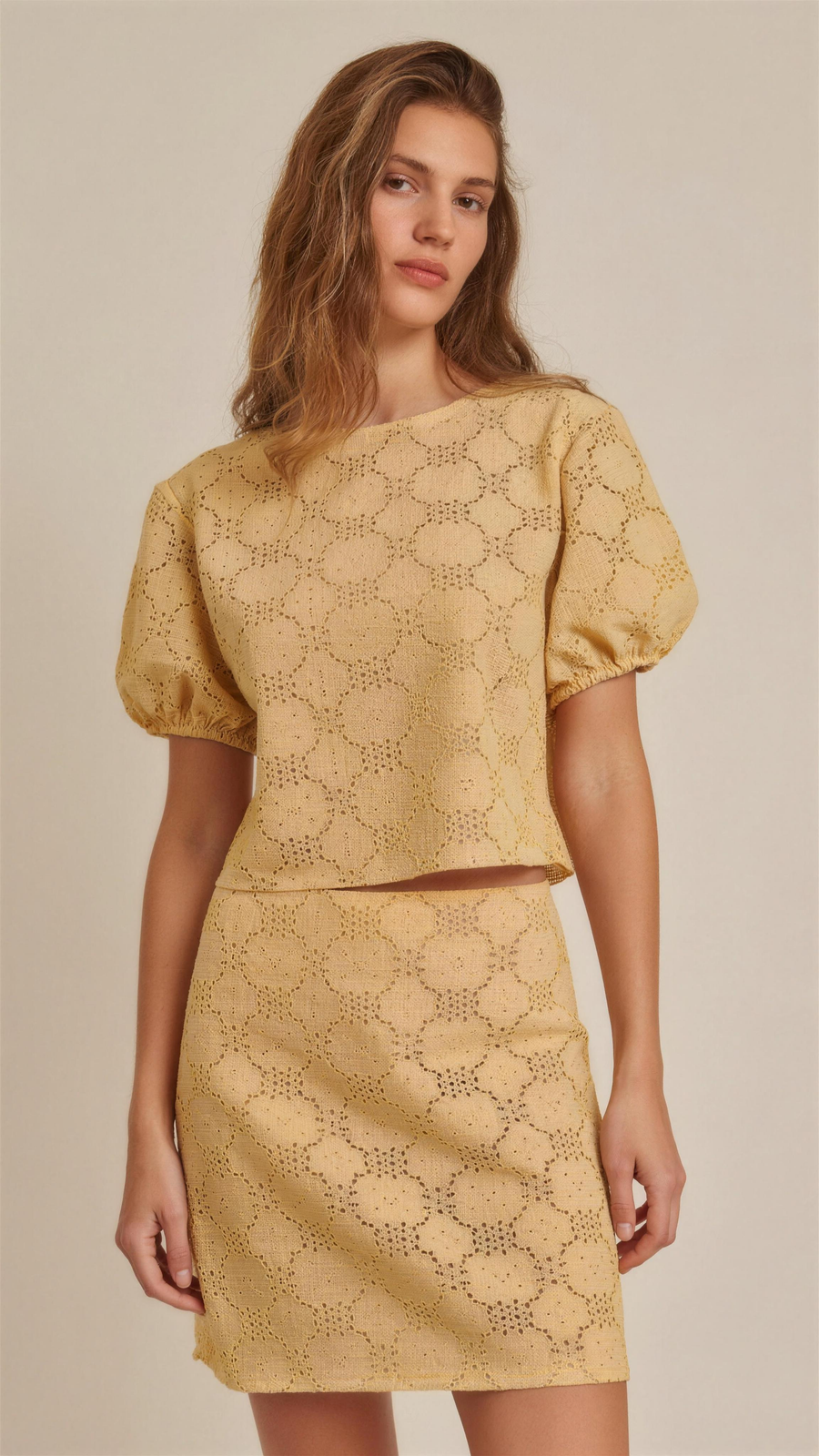 The Lisette Lace Print Blouse — editorial hero, warm apricot blouse with all-over floral lace print and hollow-out openwork, round neckline, short puff sleeves, cropped silhouette