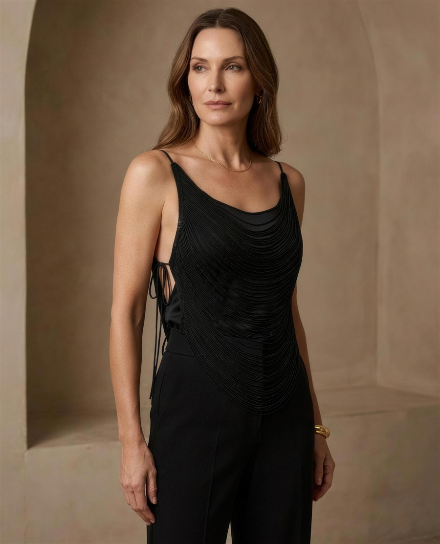 The Lyra Fringe Camisole in black, worn over a black camisole showing the hanging cord fringe and open side