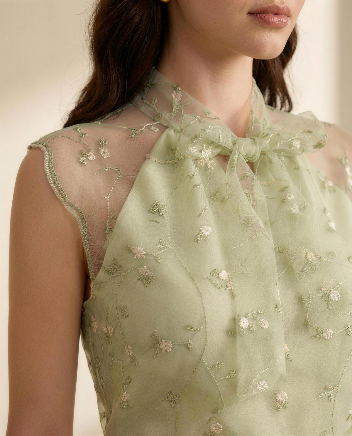 Close detail of the tonal floral embroidery, sheer organza and bow-tied collar