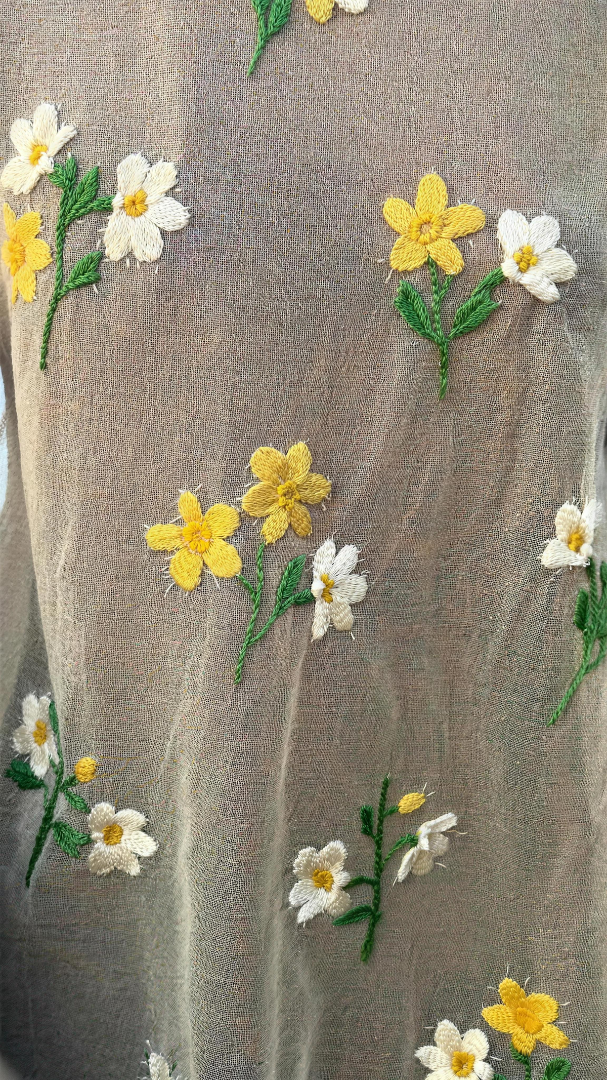 The Amalie Embroidered Floral Top — close-up of raised 3D floral embroidery on semi-sheer beige mesh, yellow and ivory flower motifs on green stems standing proud of the open mesh surface