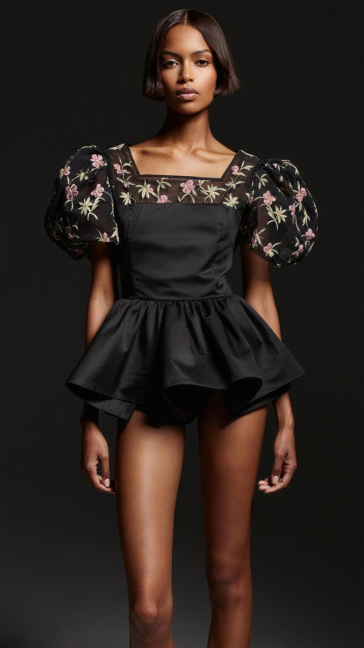 The Cecile Embroidered Peplum Blouse — editorial hero, black woven peplum blouse with contrast mesh yoke and 3D floral embroidery in pink, cream and sage, square neck, puff sleeves, flared ruffle hem